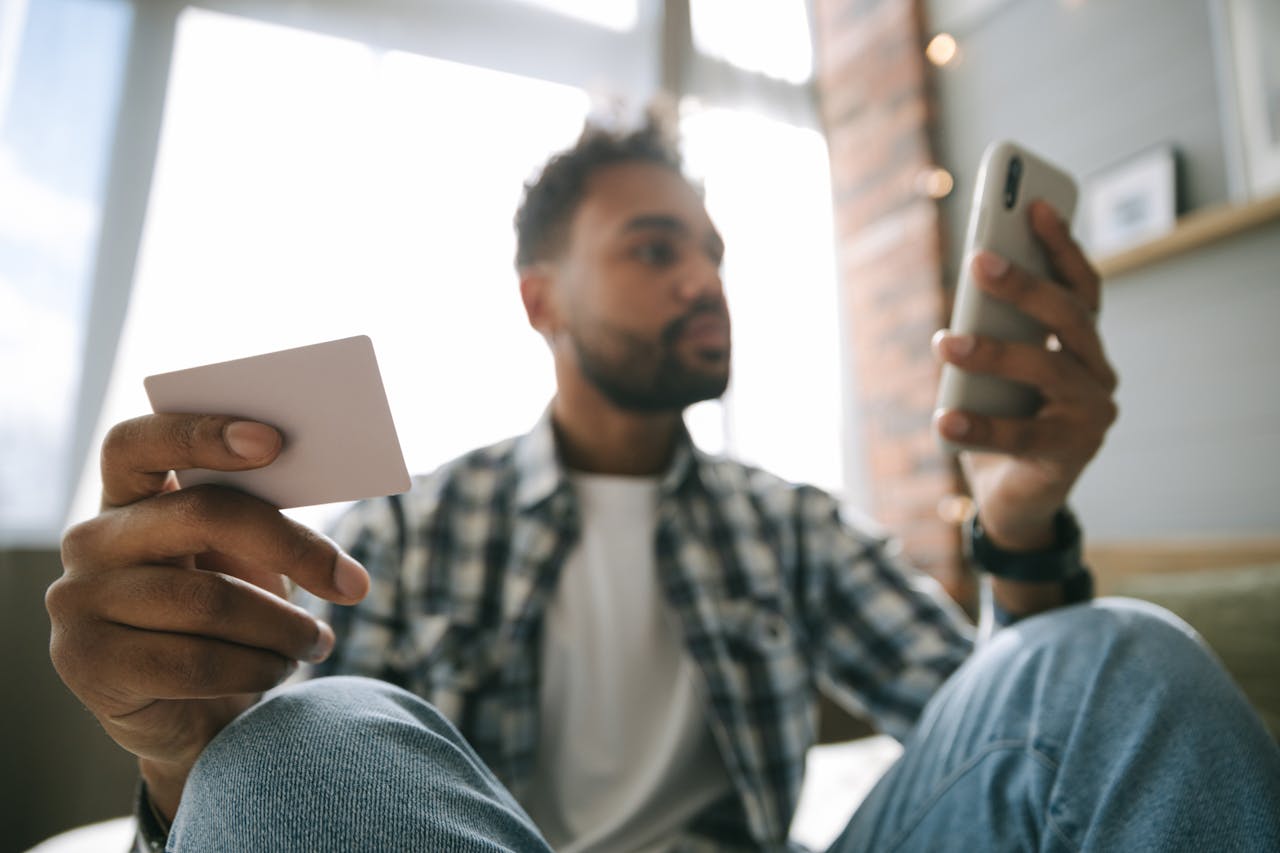 Close Up Photo of a Man Holding Cellphone and a Card